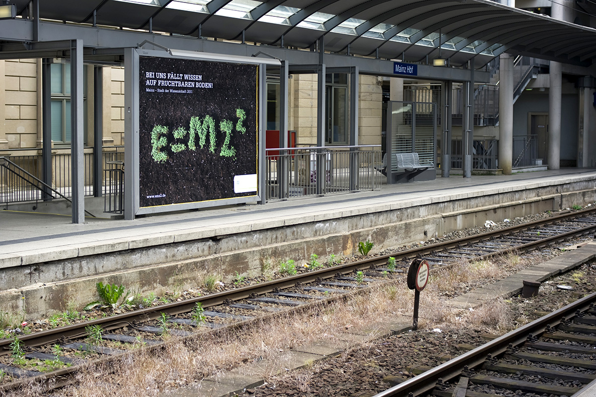 Ansicht des Plakates E=MZ² – Bei uns fällt Wissen auf fruchtbaren in Mainz am Hauptbahnhof 2011© Christian Weber – Büro für Gestaltung und Kommunikation