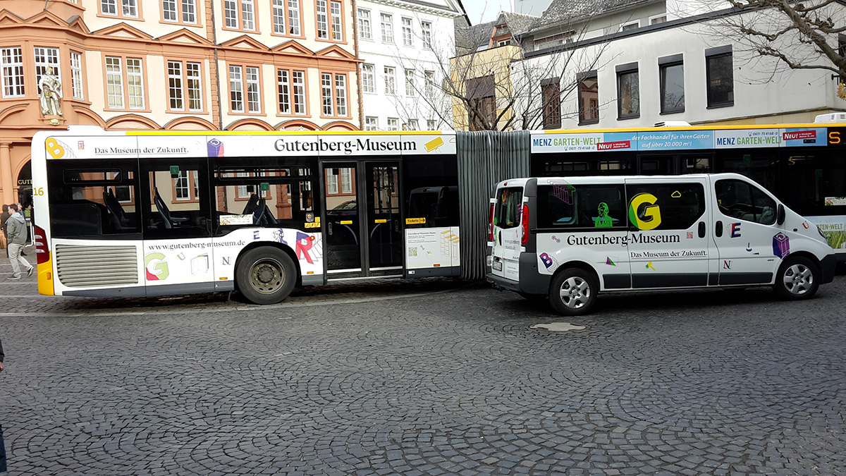 Beklebter Linienbuss und kleiner Bus stehen vor dem Römischen Kaiser – Gutenberg Museum Mainz. Das Museum der Zukunft © Christian Weber – Büro für Gestaltung und Kommunikation